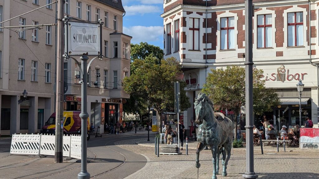 Schlossplatz Köpenick mit Pferdeskulptur und Cafés