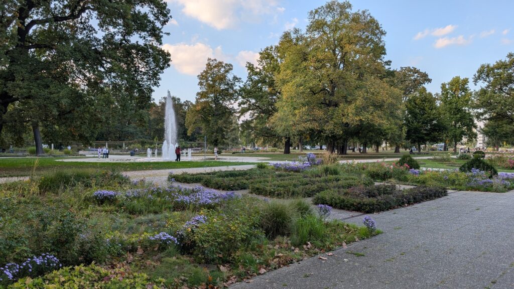 Wasserfontäne und herbstliche Bepflanzung im Rosengarten des Treptower Parks