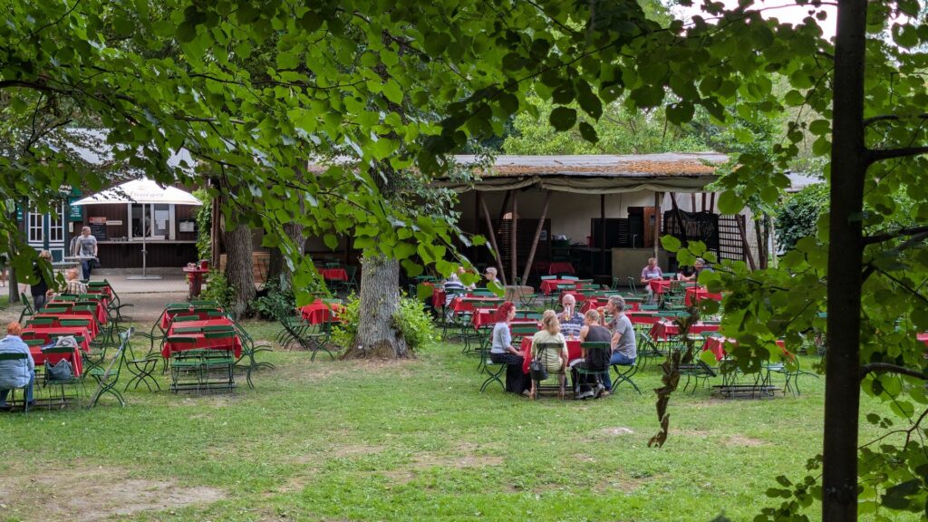 Gartenbereich der Waldgaststätte Hanffs Ruh mit Tischen unter Bäumen.