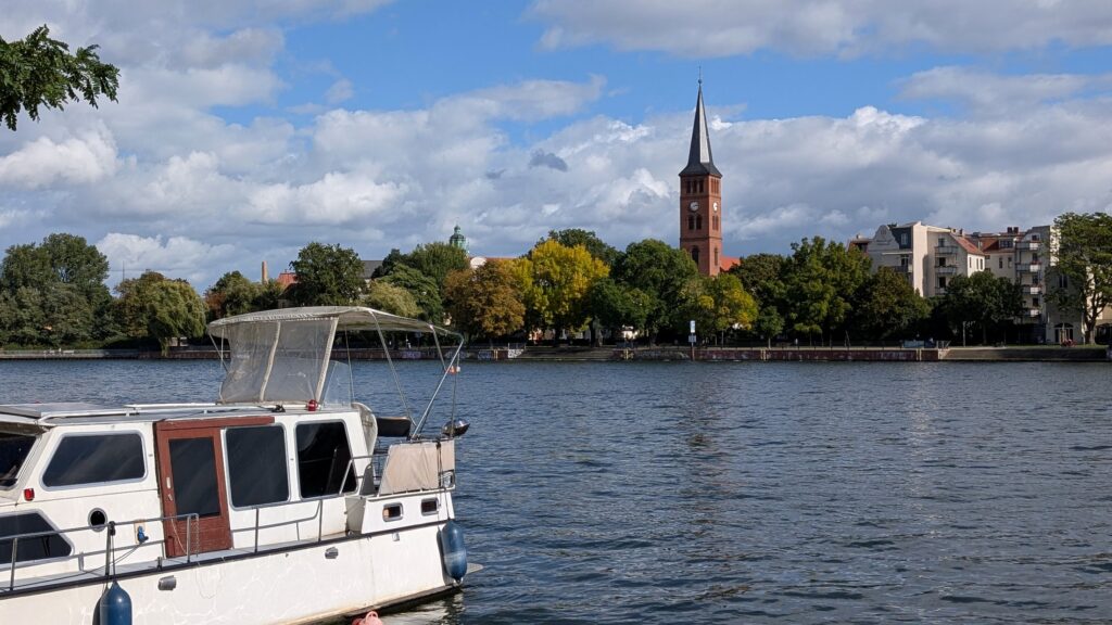 Boot auf der Dahme mit Blick vom Spindlersfelder Ufer auf Luisenhain und St.-Laurentius-Kirche