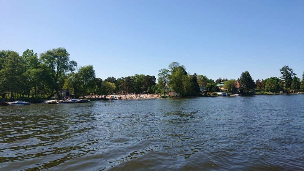 Strandbad Eichwalde vom Wasser aus mit Badenden am Ufer
