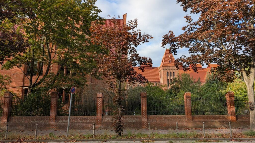 Historische Backsteinbauten des Wasserwerks Friedrichshagen hinter altem Baumbestand