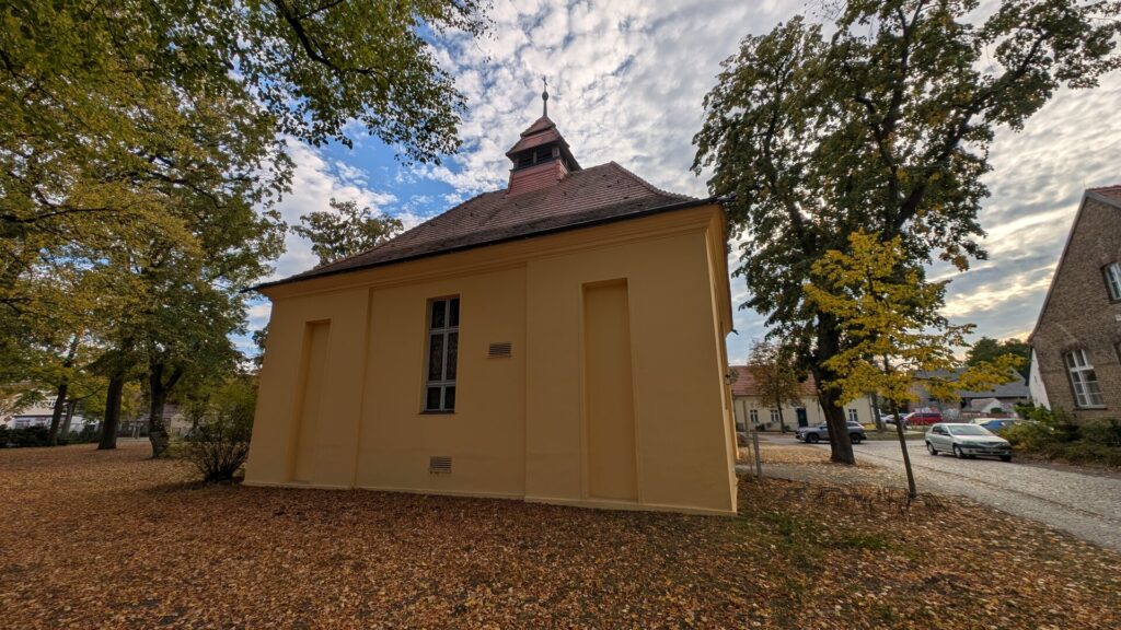 Dorfkirche Müggelheim unter herbstlichen Bäumen von der Rückseite