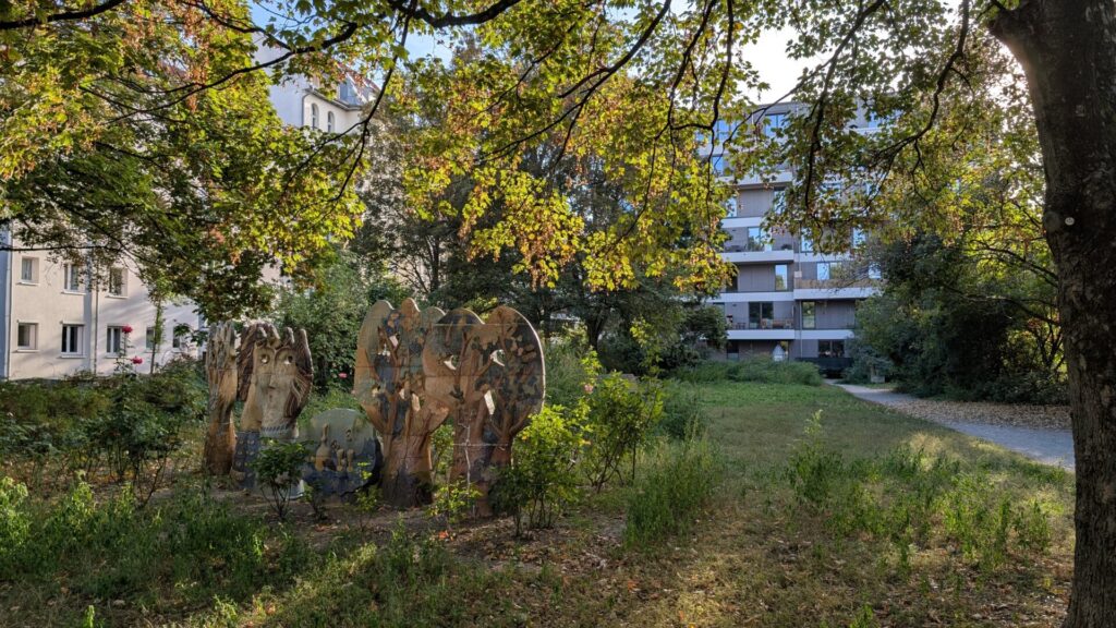 Figürliche Skulpturen unter alten Bäumen auf dem Schmollerplatz in Alt-Treptow
