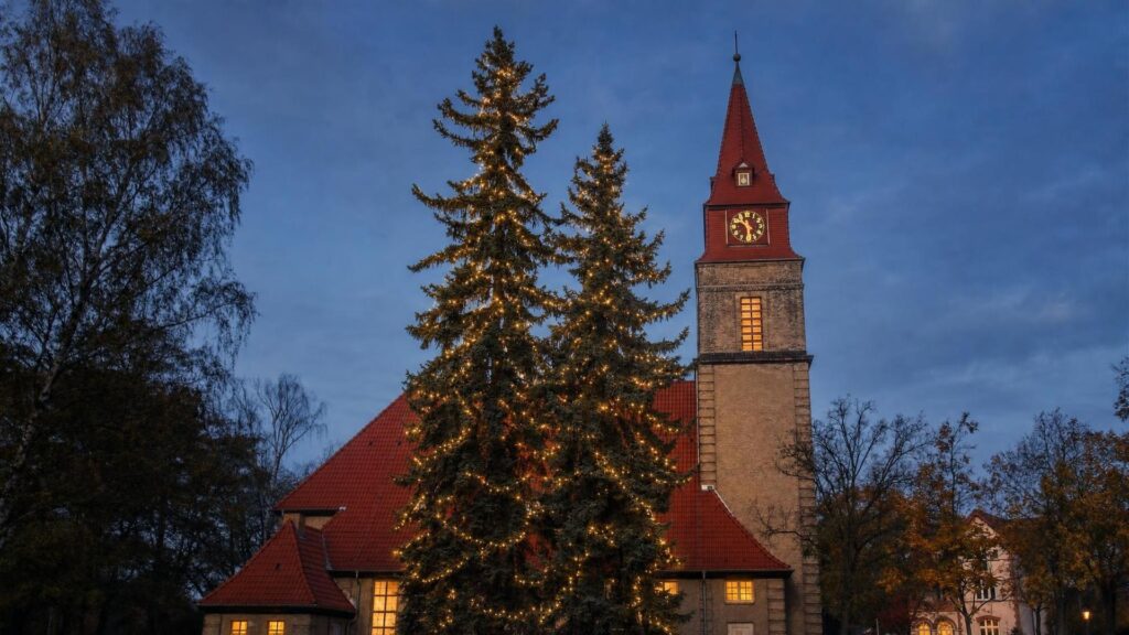 KI-Illustration: Taborkirche Wilhelmshagen zur blauen Stunde mit beleuchteten Tannen