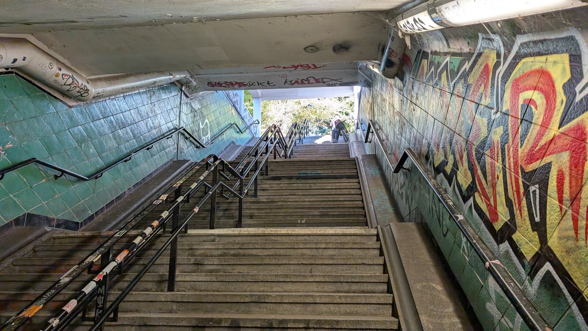 Treppenaufgang des Spreetunnels mit historischen Wandfliesen und Graffiti